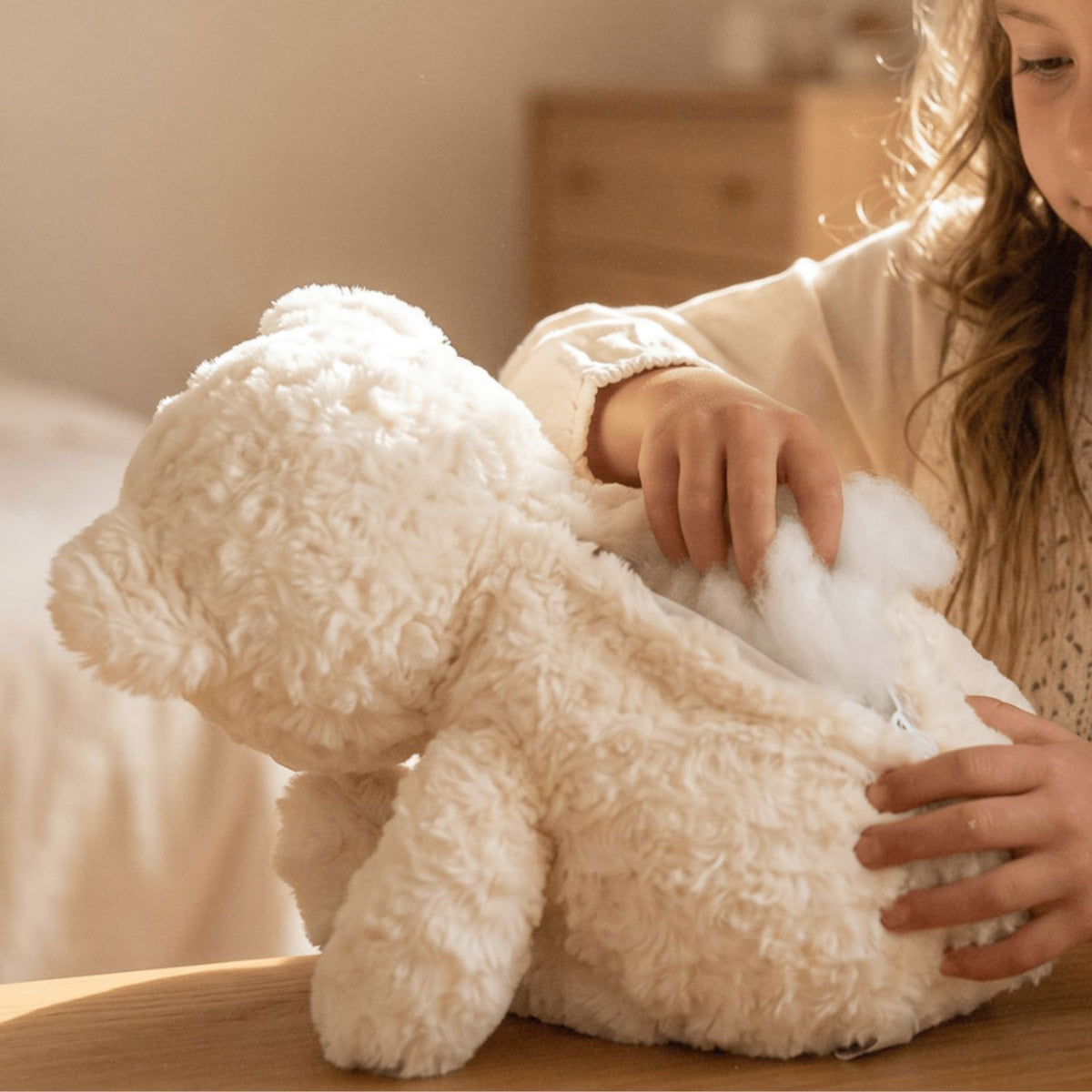 Une fille fabrique son nounours en peluche crème